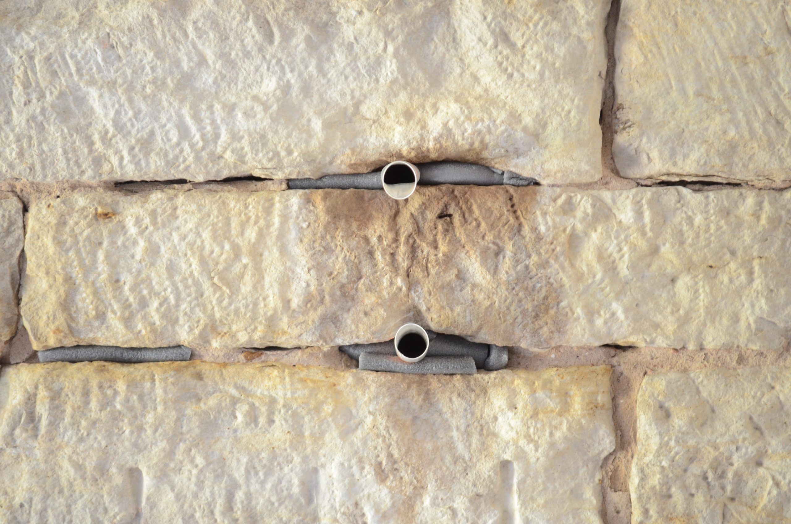 Exclusion tubes installed in mortar joints of stone bridge - humane bat exclusion