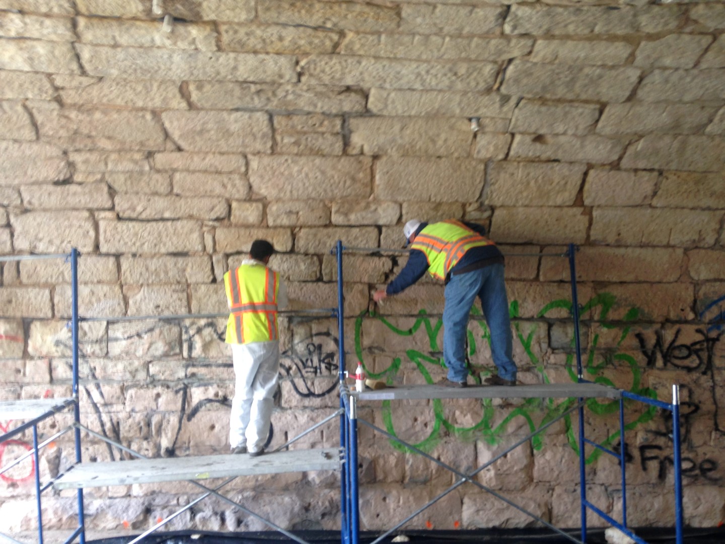 Workers in high-visibility vests performing bat exclusion on stone bridge